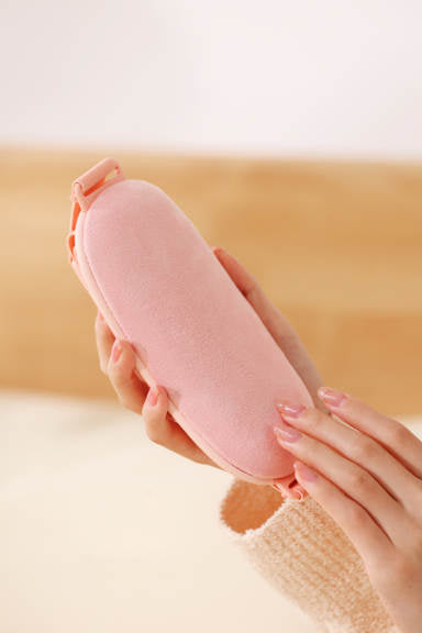 Hands holding a pink menstrual pain relief massager designed for comfort and targeted cramp relief.